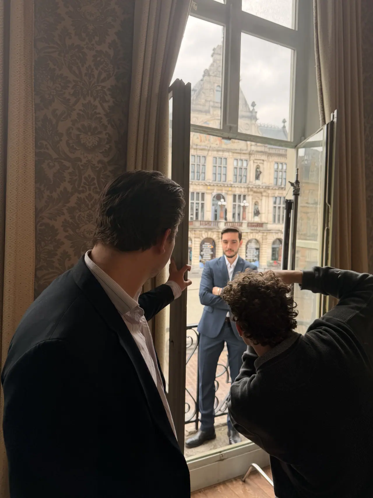 Een fotograaf van VBS schiet een portret aan het raam, met het Sint-Baafsplein buiten