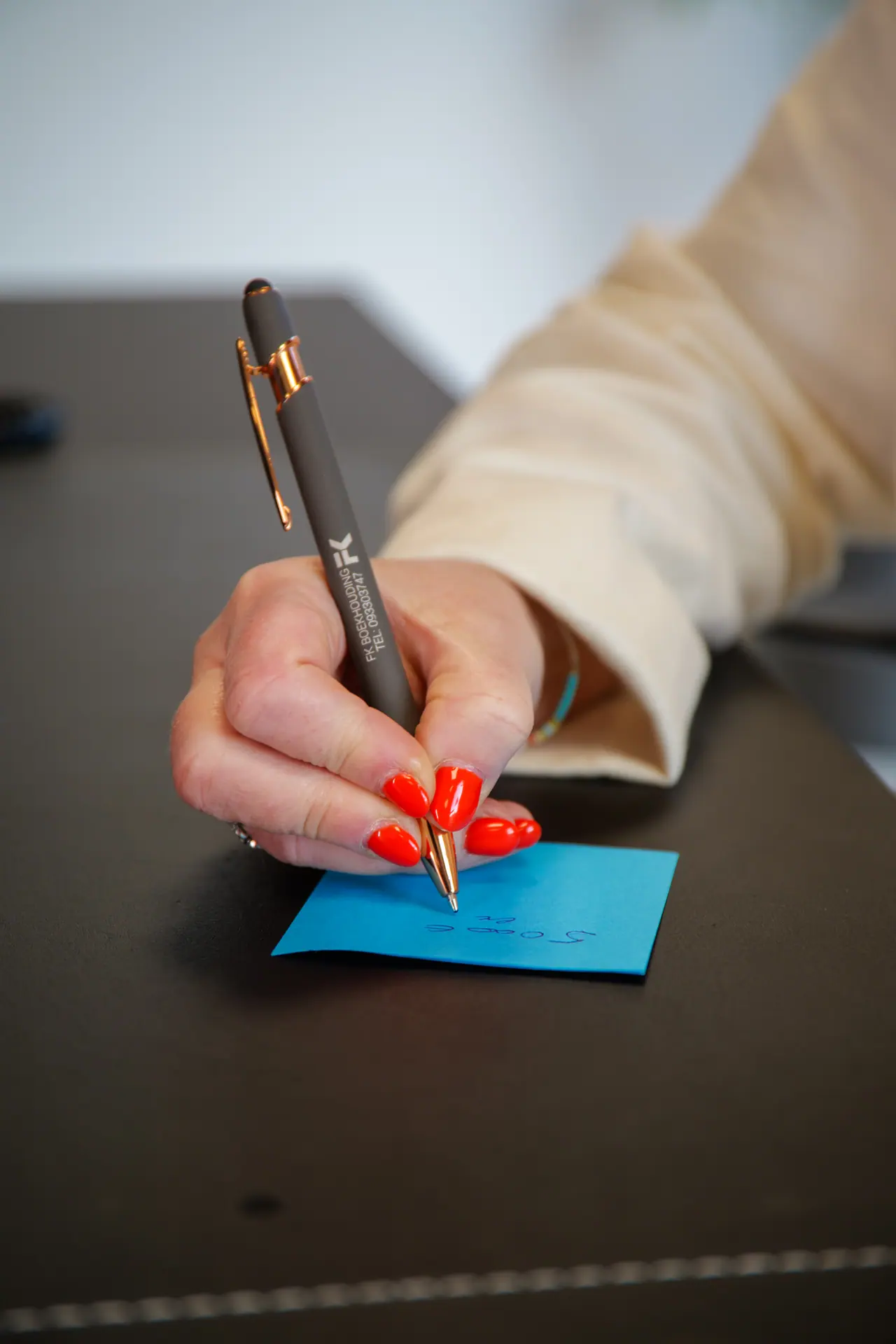 Een hand schrijft met een FK-pen op een notitie
