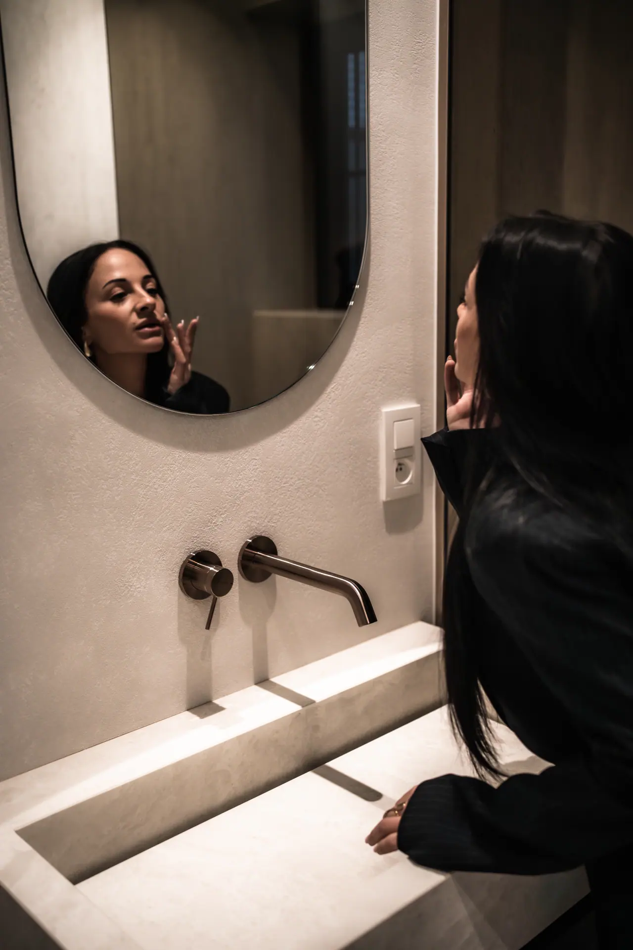 A finished bathroom with a round mirror by SN Group