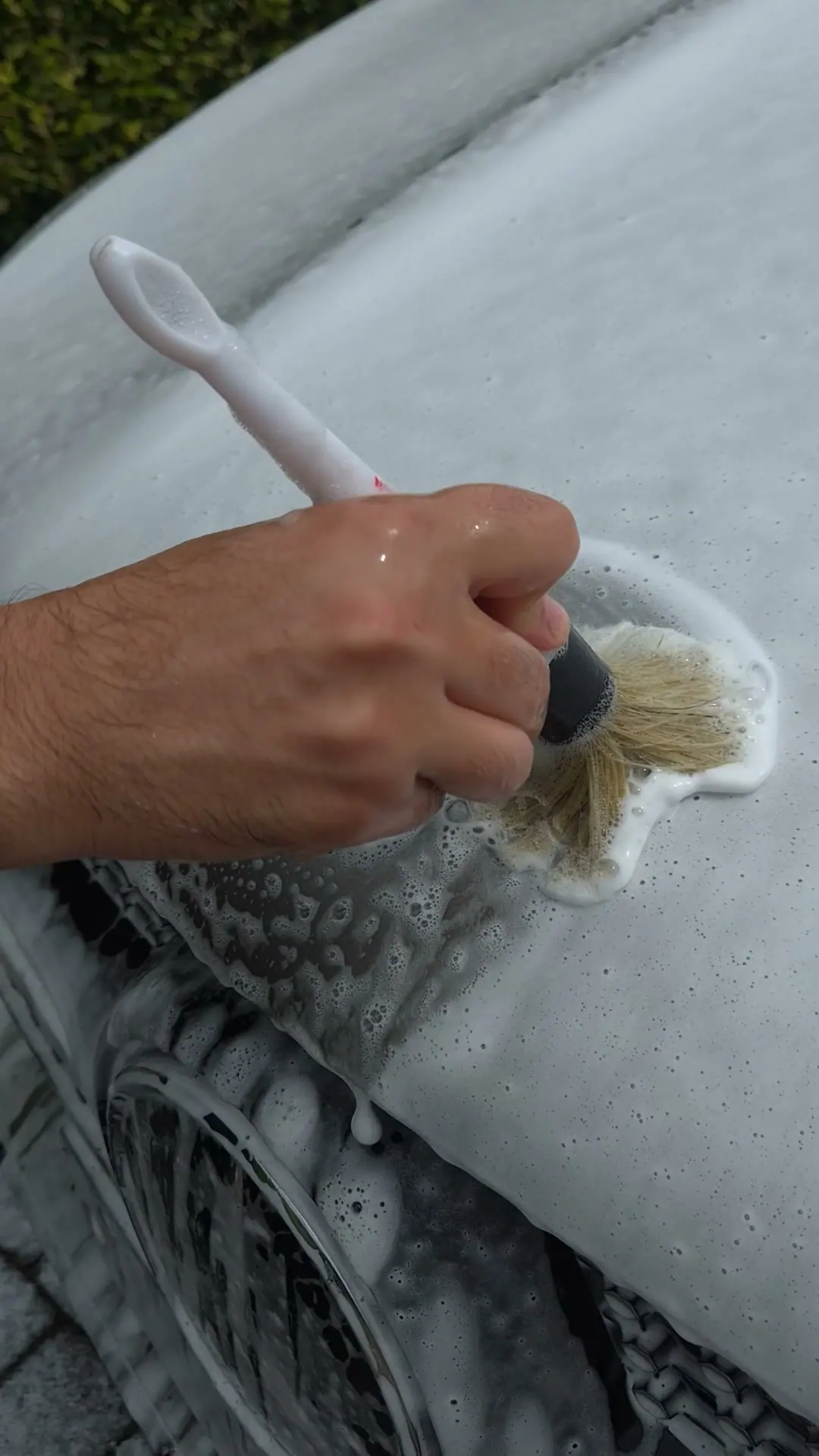 A car in foam with a brush next to the logo, from the footage for Park & Wash