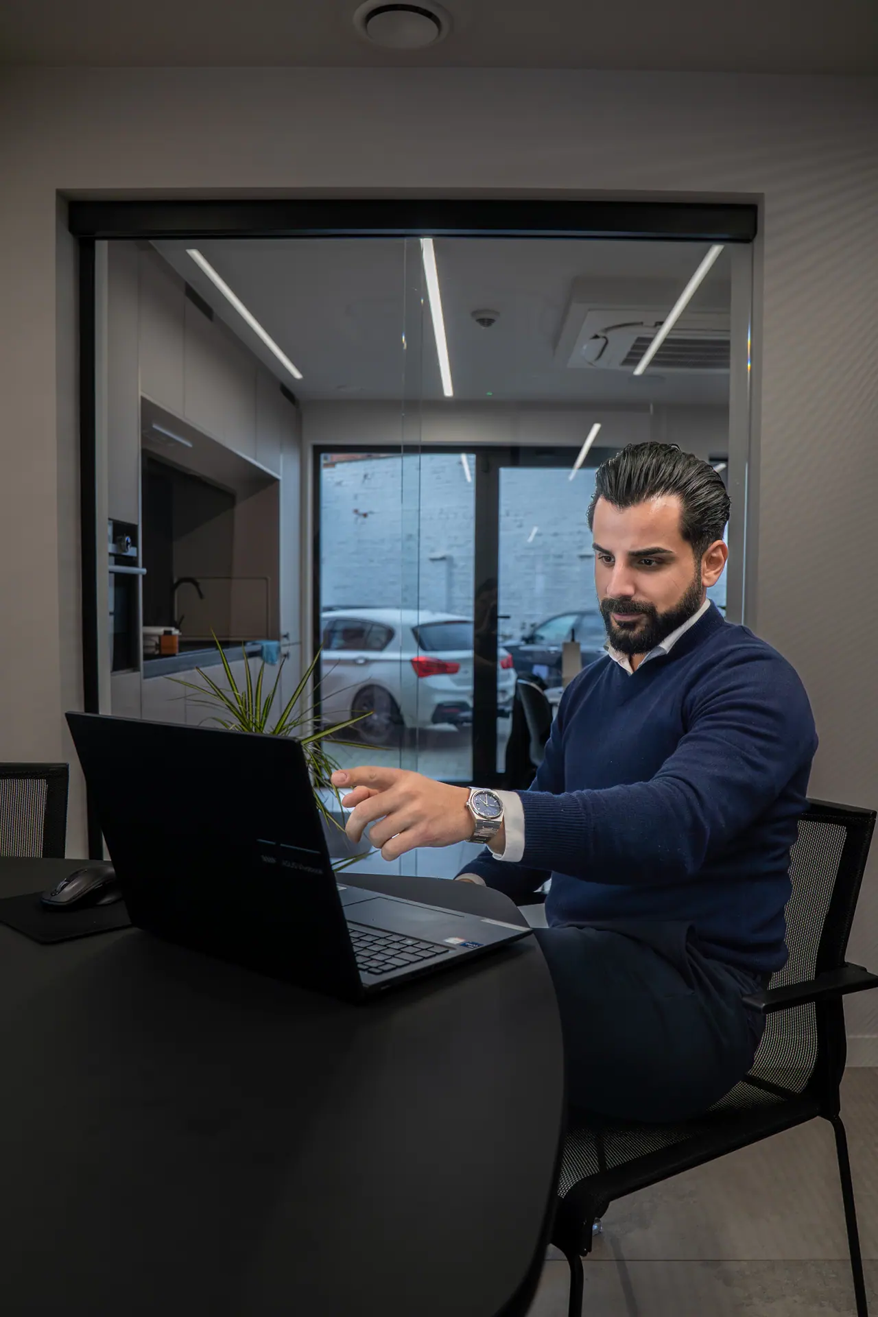 AI trends 2027 for European businesses: a business owner at his laptop in a glass-walled meeting room, planning next year's work