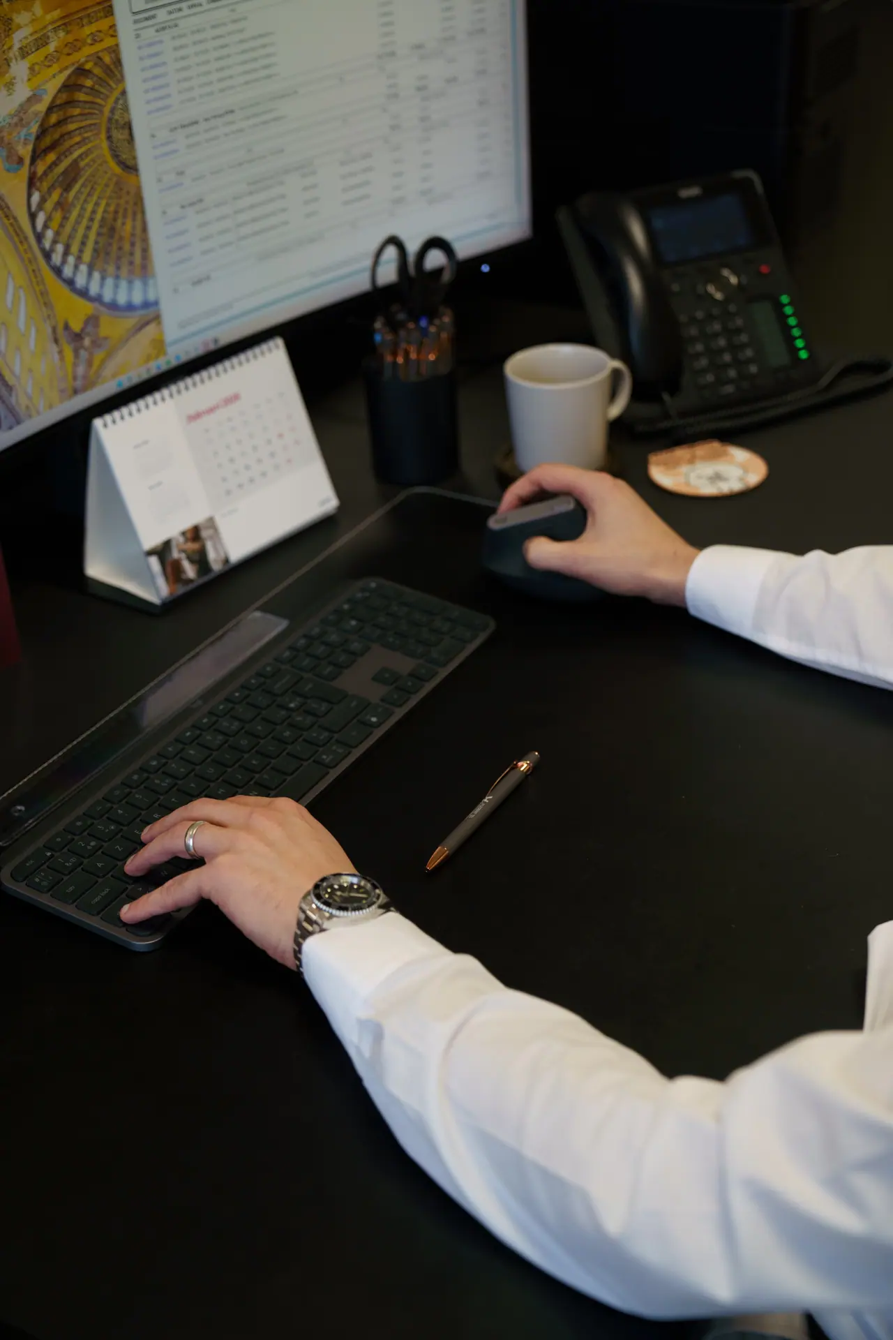 Een hand aan een laptop en een muis op een donker bureau, het dagelijkse werk waar AI tools voor bedrijven in passen