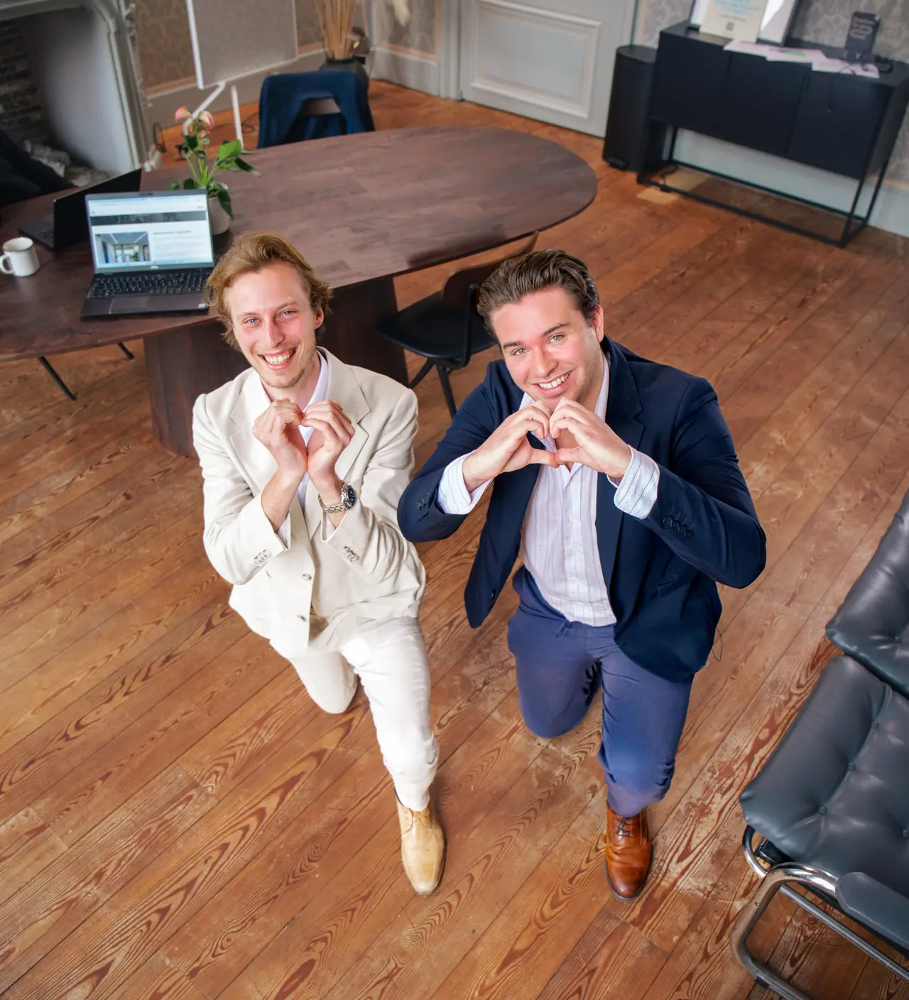 Twee collega's van VBS vormen een hartje met hun handen, van boven gefotografeerd
