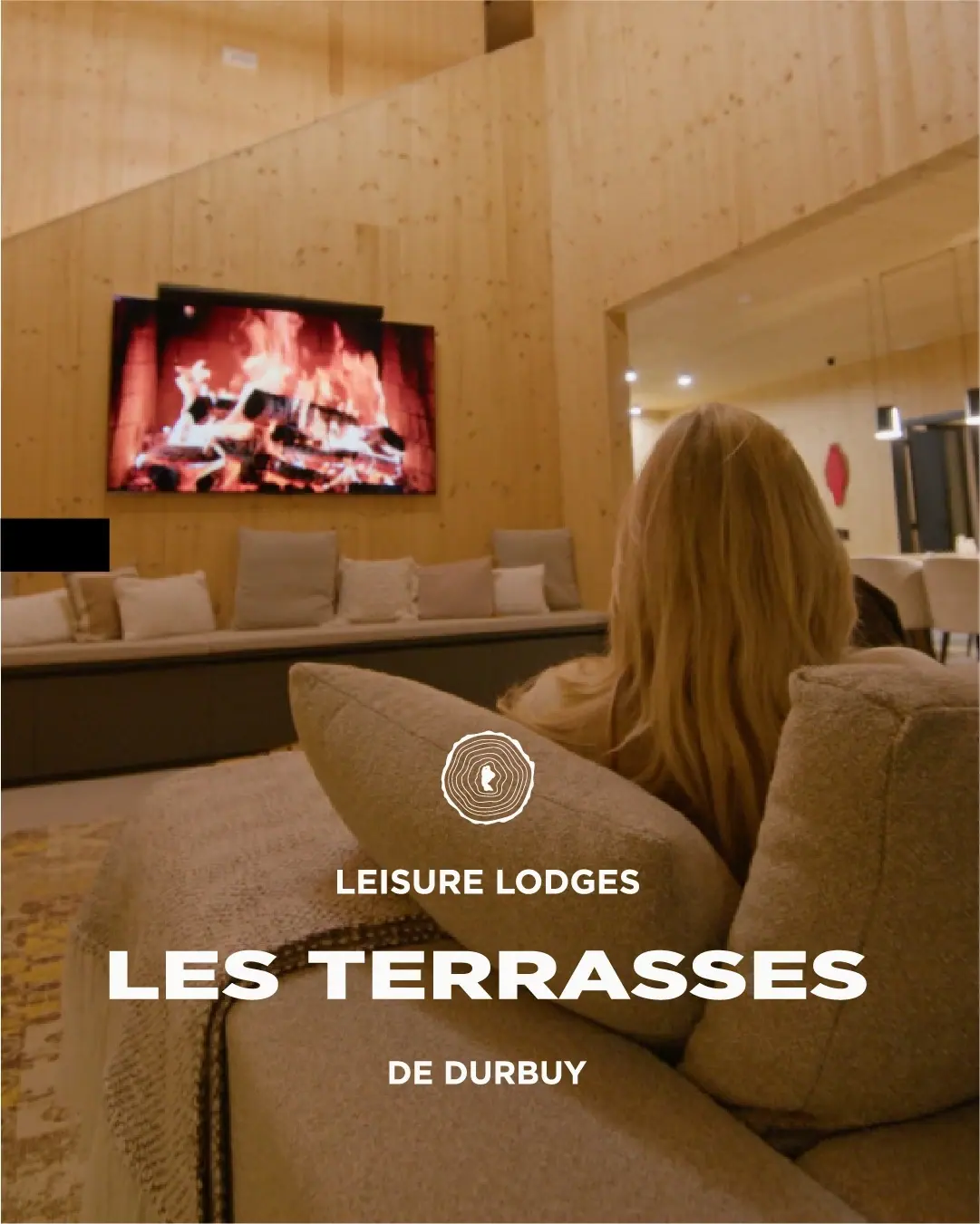 Les Terrasses de Durbuy ad with a guest by the fireplace