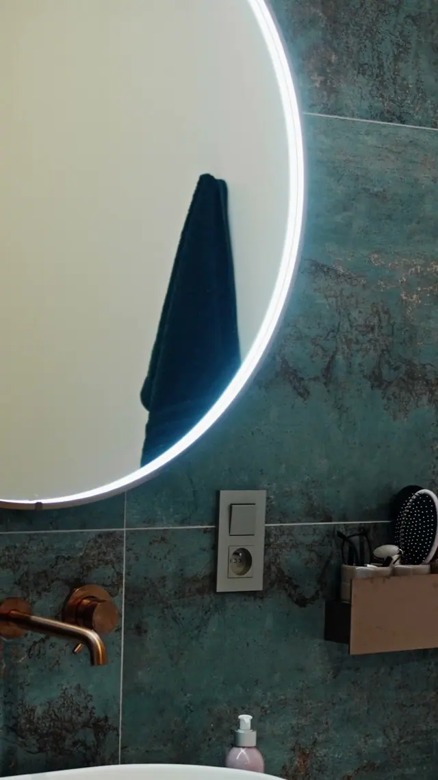 A bathroom with a round mirror, from an SN Group reel